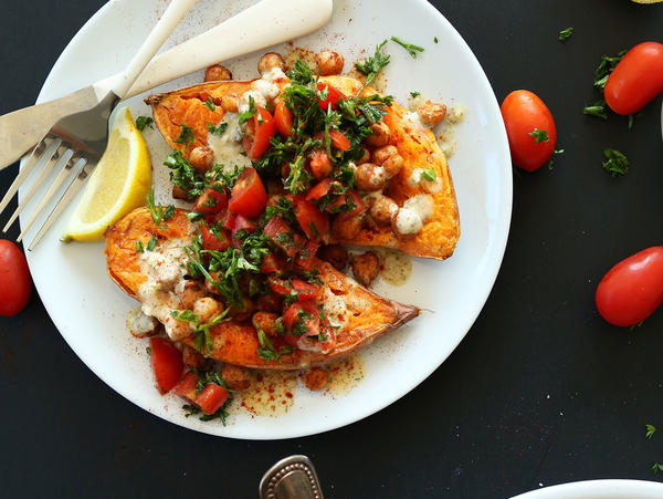 A bowl of Mediterranean Baked Sweet Potatoes with a knife and fork beside it